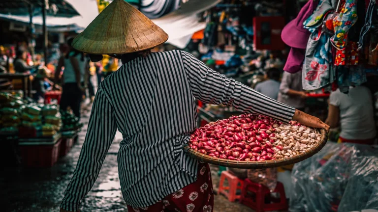 Người bán hàng đội nón lá mang thúng hành tỏi tại chợ Đông Ba, Huế